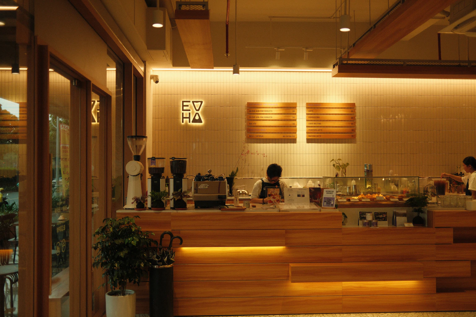 Baristas working behind a wooden cafe counter.